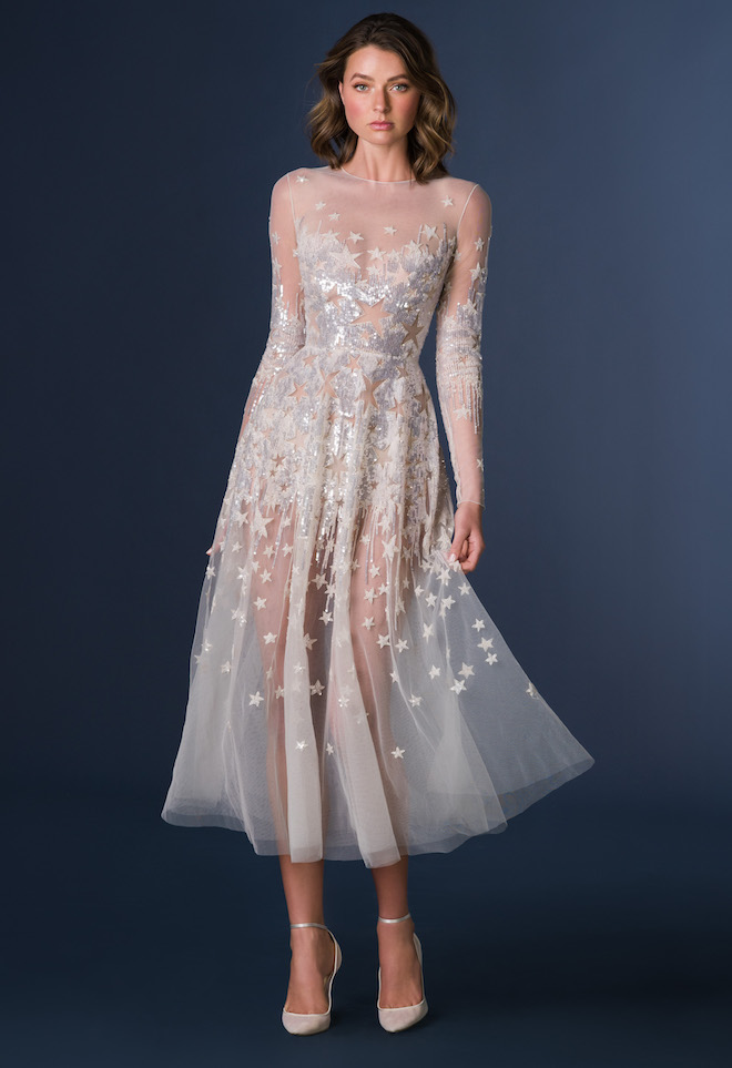 Model wearing a mid length sheer gown bedecked with stars.