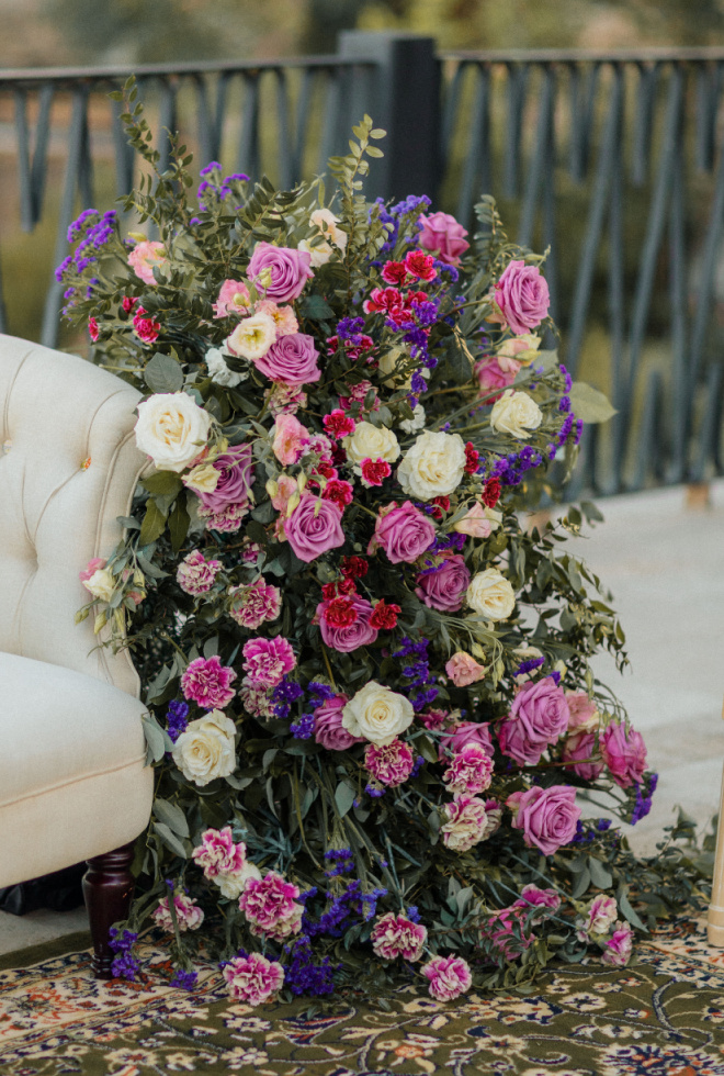 White, purple and fuchsia colored florals by Malleret Designs decorate the alter. 