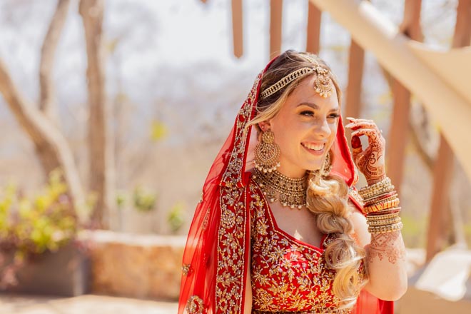 The bride smiles while wearing traditional Indian wedding attire for her destination wedding in Mexico.