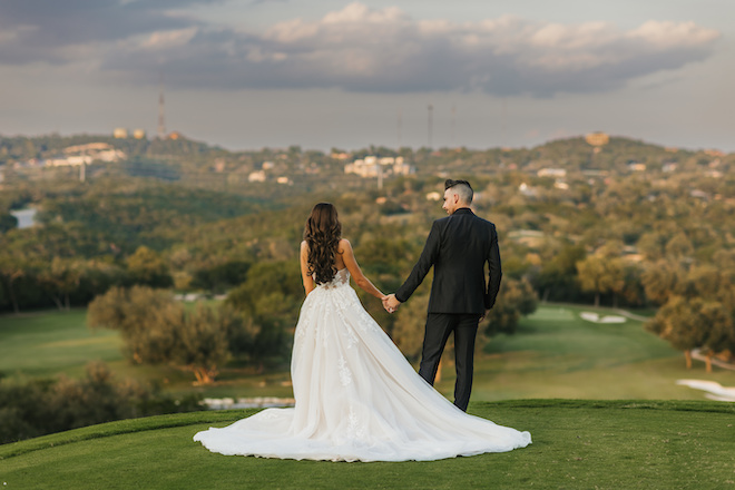 A bride and groom holding hands on the lawn on Omni Barton Creek Resort & Spa overlooking the hill country. 
