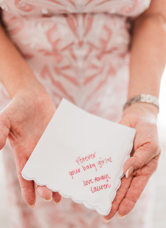 The bride's mother holding a handkerchief reading "Forever your baby girl. Love always, Lauren"