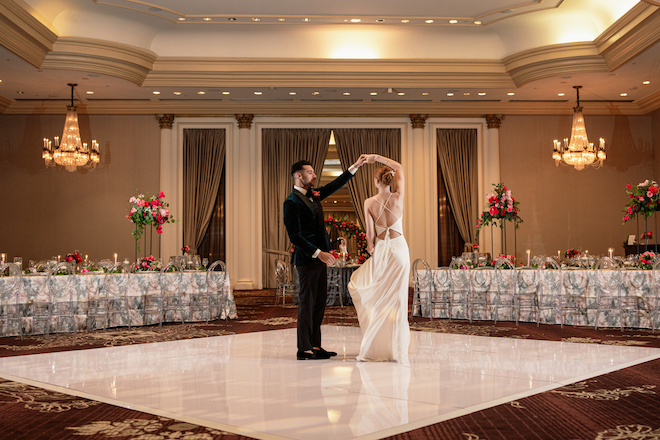 A bride and groom dancing on a white dancefloor in the ballroom of the Hilton Houston Post Oak. 