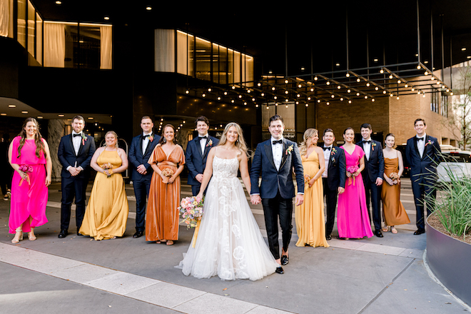 A bride and groom walking with their wedding party in the front of the Four Seasons Hotel Houston. 