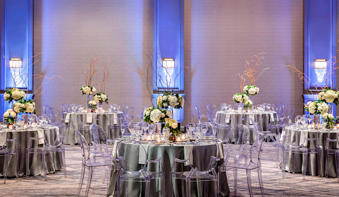 Five round tables with green linens and floral centerpieces in a ballroom at the JW Marriott Houston by the Galleria. 