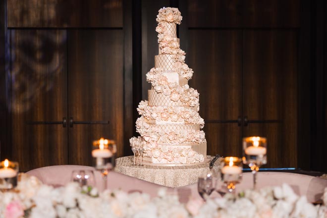 Cakes by Gina designs an 8-tier wedding cake decorated with fondant florals and gold accents. 