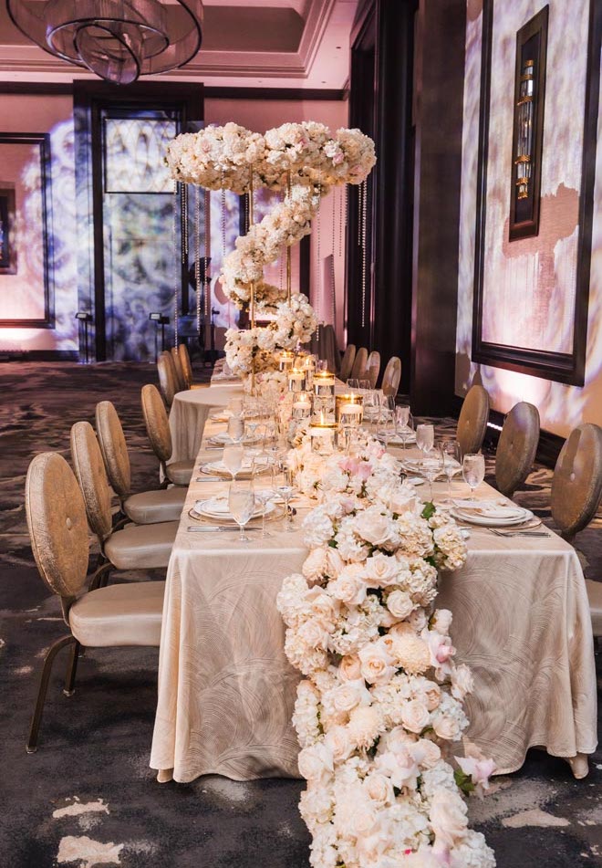 White dripping floral instillations detail the tables at the glamorous ballroom reception.