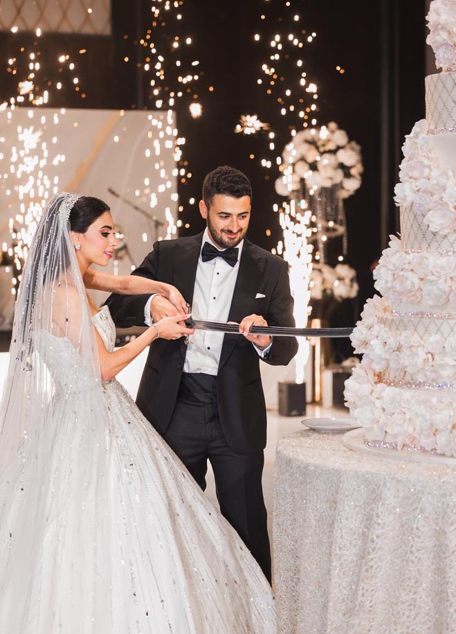 The bride and groom cut into their eight-tier wedding cakes with a sword.