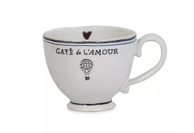 A white coffee cup with a heart on the inside, and a hot air balloon with the words "Cafe de L'amour" on the outside. 