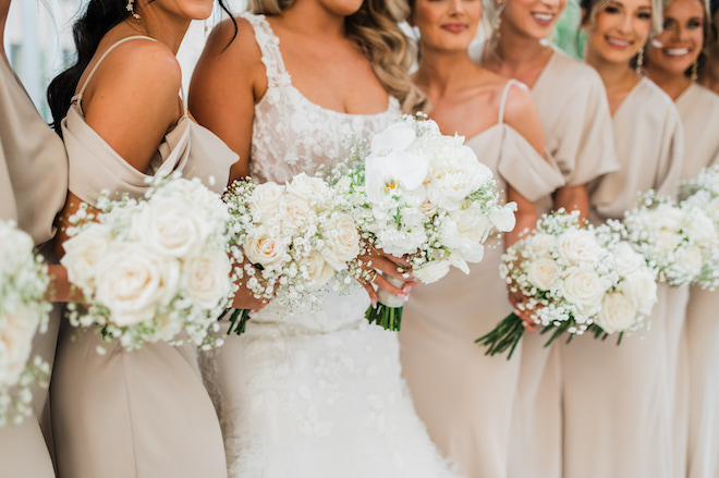 The bride and bridesmaid bouquets holding white floral bouquets with baby's breath.