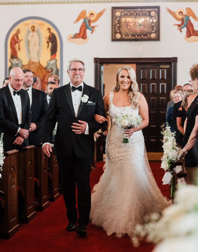 The bride and her father walking down the aisle in a church. 