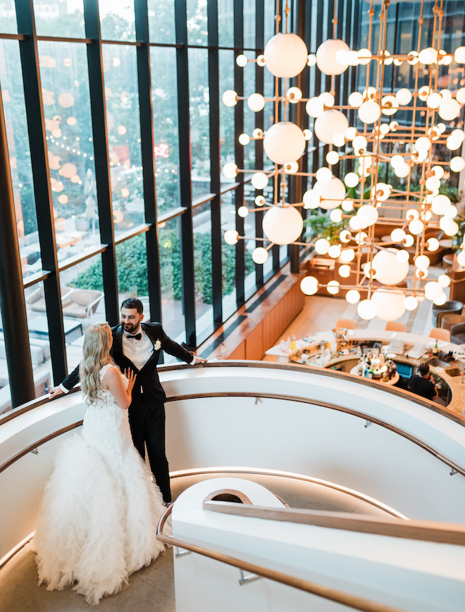 The bride and groom standing on the spiral staircase overlooking the bar of the C Baldwin Hotel. 