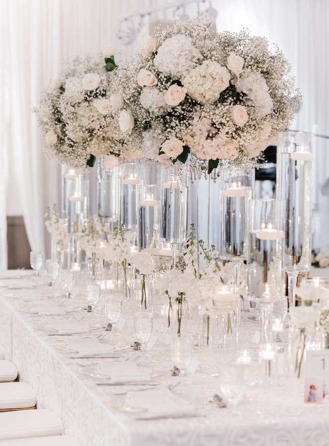 A reception with white floral centerpieces with baby's breath, hydrangeas and roses and floating candles. 