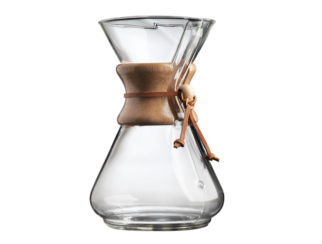 A glass carafe with a brown handle. 