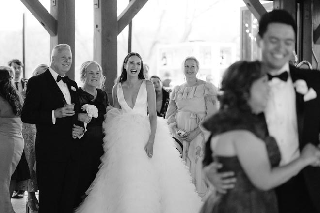 The bride and her parents watch the groom and his mother share their first dance. 