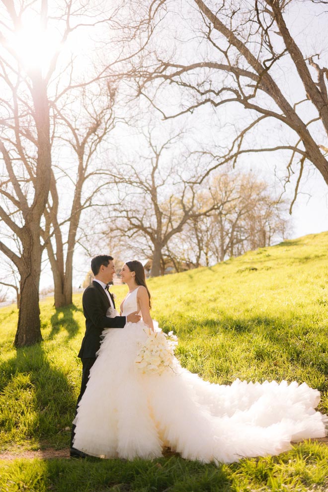 The bride and groom stand outdoors of their wedding venue in the Texas hill country.