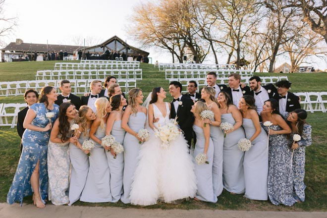 The bride and groom smile with their wedding party outside their wedding venue, Hyatt Regency Lost Pines Resort & Spa.