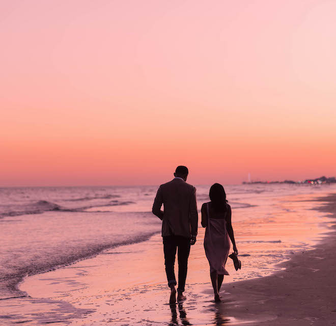 A couple walking along the Galveston beach at sunset. 
