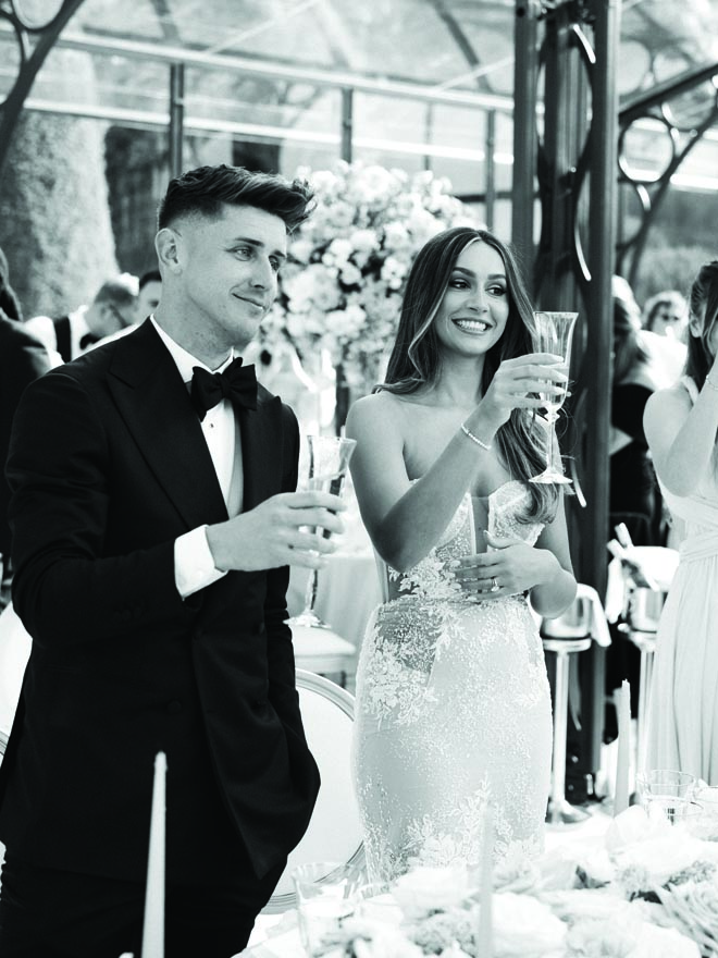 The bride and groom raise a glass of champagne at their dinner party.