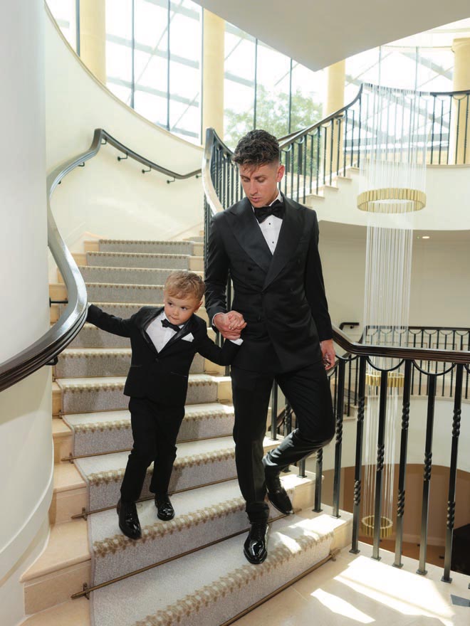 The groom and his son hold hands as they walk down the stairs of the England wedding venue. 