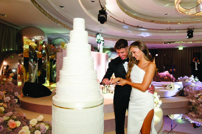 The bride and groom cut into the their six-tier white wedding cake. 