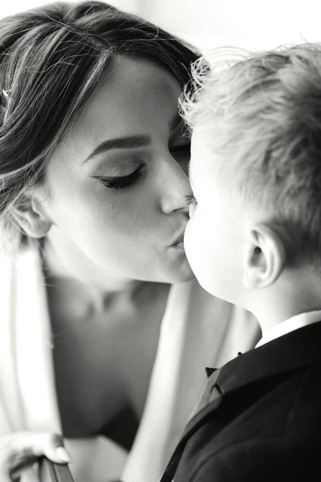The bride gives her son a kiss while getting ready for her wedding. 