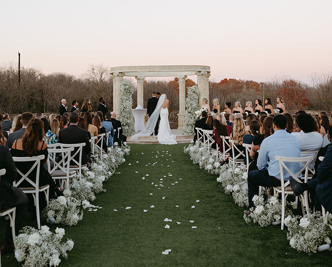 The aisle lined in baby's breath and flower petals with the bride and groom at the altar. 