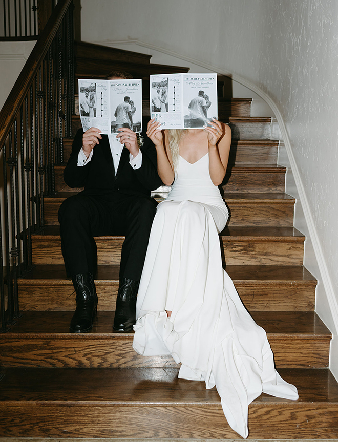 The bride and groom holding up their programs that look like newspapers called "The Newlywed Times".