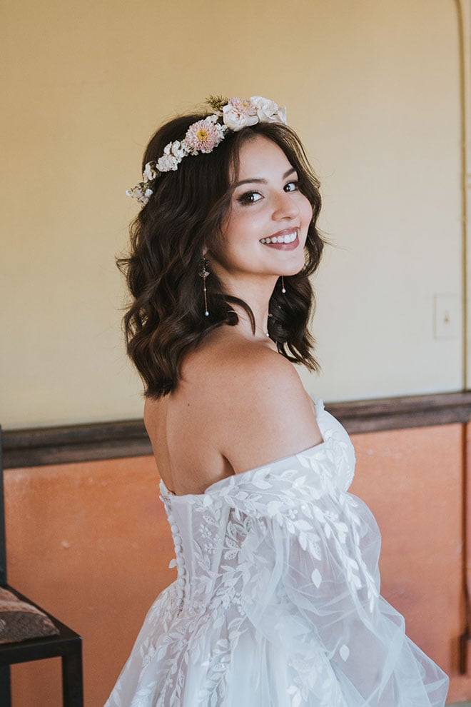 The bride smiles wearing a floral headband for her art nouveau wedding.