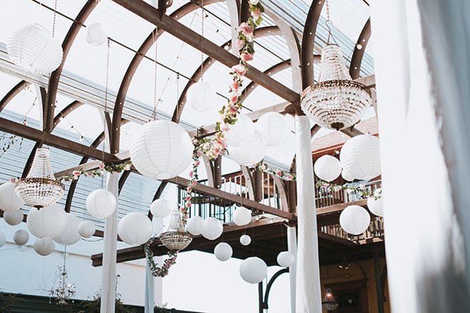 Greenery and pastel florals drape the ceiling of AvantGarden for the couple's art nouveau wedding.