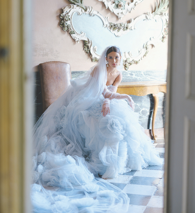 The bride posing in her blue wedding dress with a blue veil and gloves. 