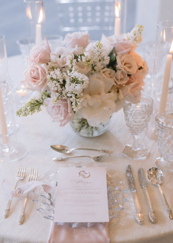 A pink and white tablescape with a floral centerpiece. 