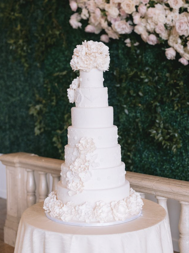 A white seven-tier wedding cake decorated with florals.