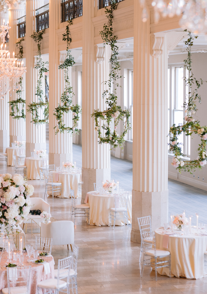 The Corinthian Houston decorated with chandeliers, lanterns decorated in greenery and tables decorated with large white and blush floral centerpieces.