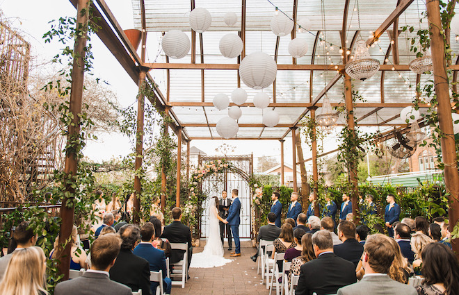 The bride and groom hold hands at the altar at their outdoor wedding ceremony at AvantGarden.