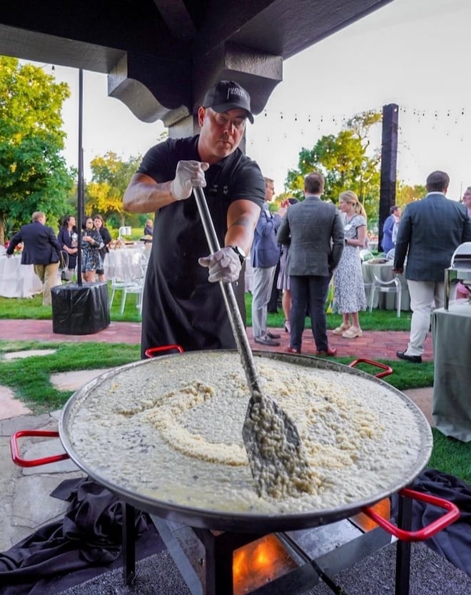 Masraff's Catering team member stirs the food in the pot at the black truffle risotto station. 