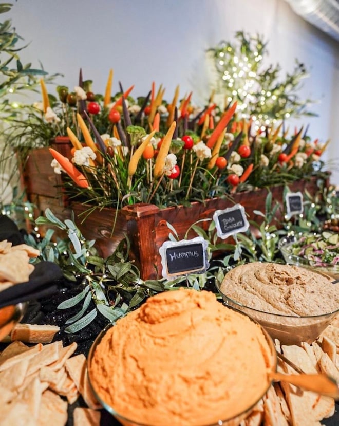 Bowls of hummus and vegetables from Masraff's Catering are displayed at a Houston event.