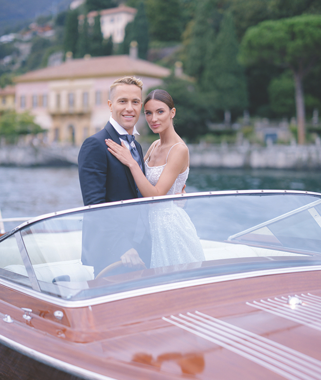 The bride and groom posing on a boat on Lake Como, Italy. 