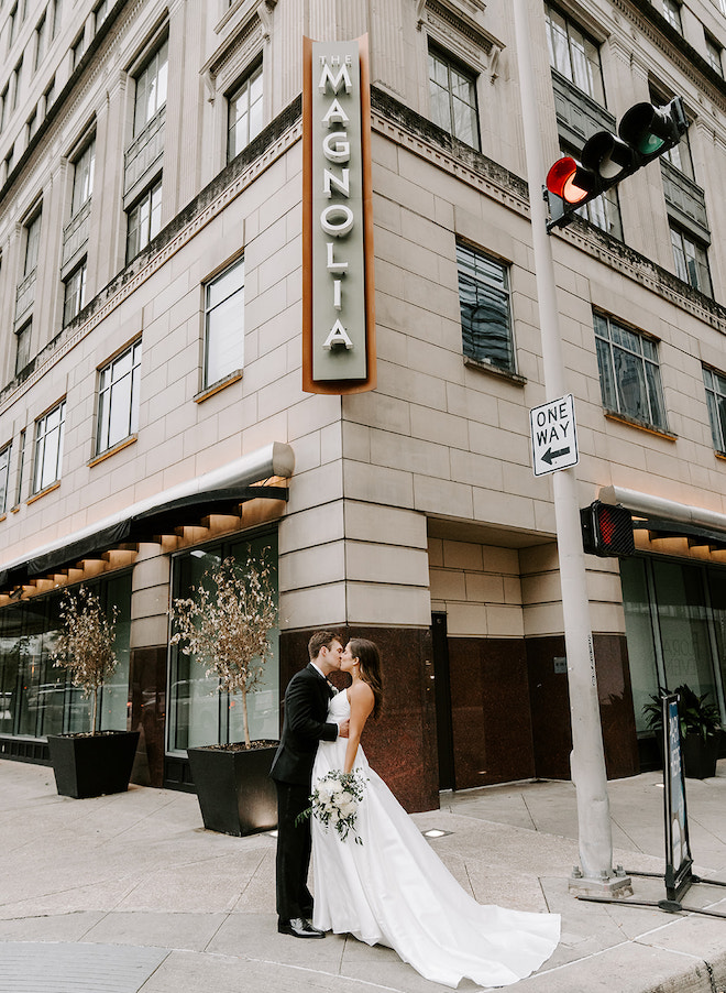 The bride and groom share a kiss outside of the Magnolia Hotel Houston.