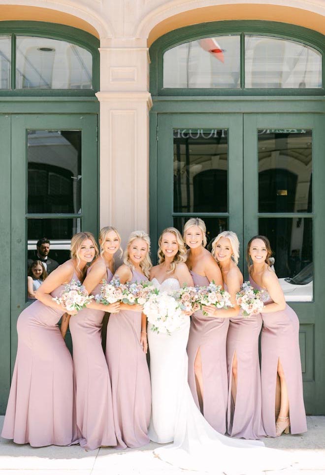 The bride and bridesmaids stand outside their wedding venue in Galveston, Texas.