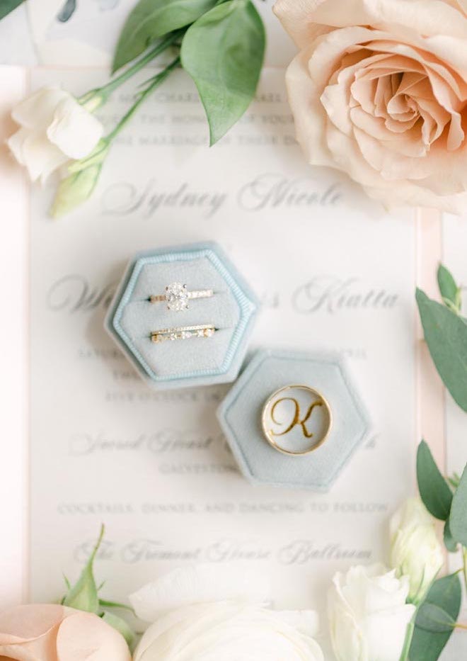 The bride and groom's wedding bands sit on top of their blush colored stationery and invitations.
