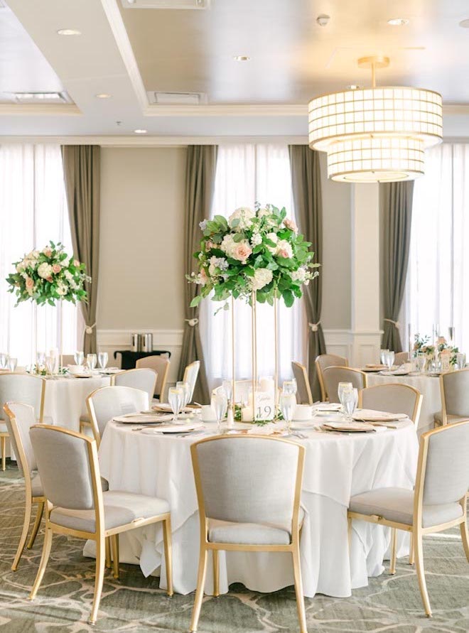 White and blush floral centerpieces decorate the reception table at a light and airy wedding.