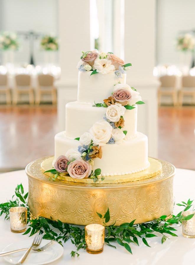 A three-tier white wedding cake is served at a light and airy wedding.
