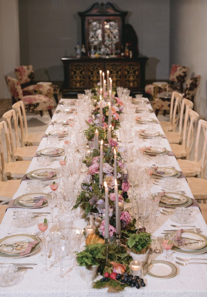 A long table with candles, florals and green and pink china. 