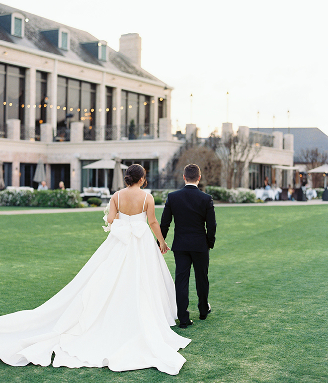 The bride and groom holding hands walking down the lawn of the country club. 