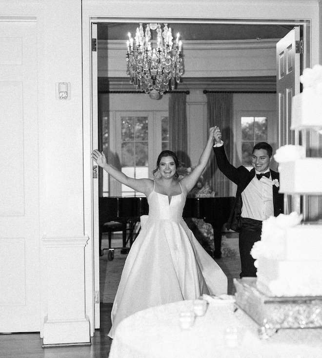 A bride and groom cheering as they walk into their reception. 