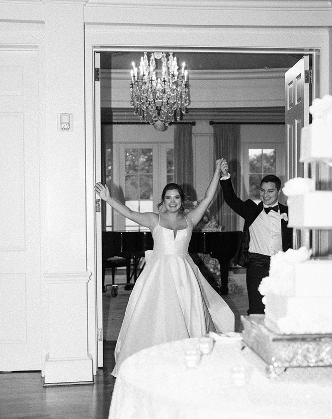 The bride and groom holding hands walking into the ballroom.