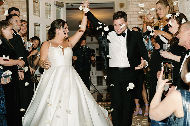 The bride and groom holding hands with a flower petal send off. 