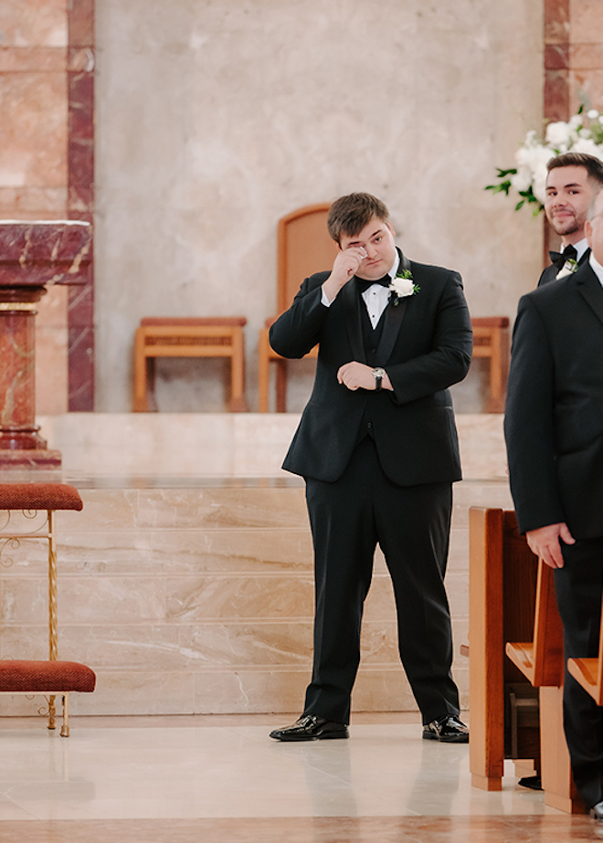 The groom wiping a tear from the altar of the church. 