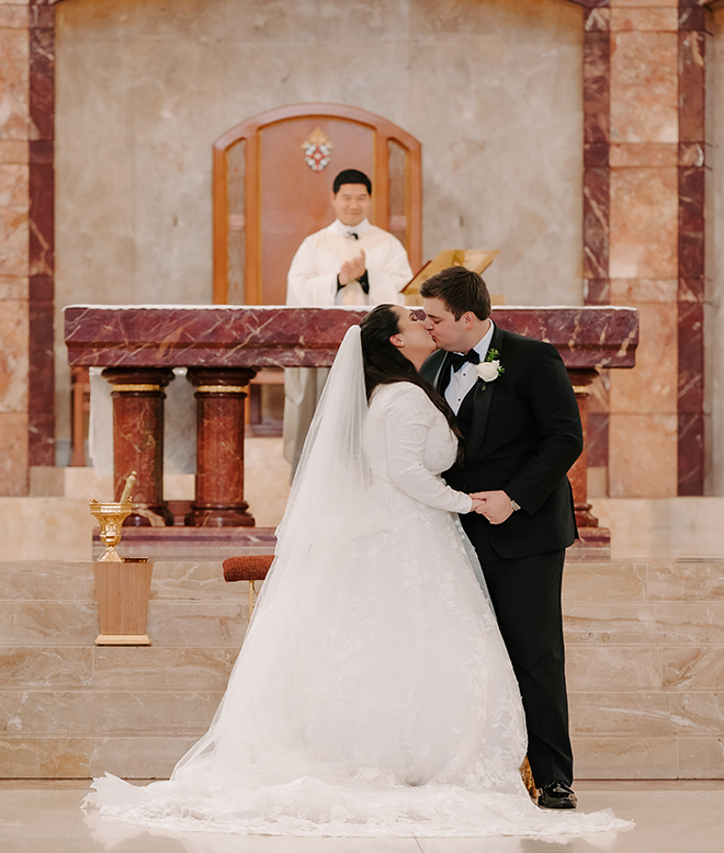 The bride and groom kissing at the altar. 