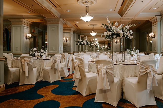 The Hotel ICON ballroom decorated with white linens and white and green floral centerpieces. 